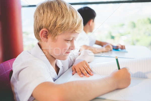 Stock photo: Schoolkid doing homework in classroom
