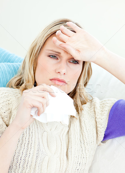 Ill woman holding a tissue sitting on a sofa at home Stock photo © wavebreak_media