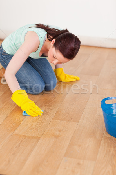 Pretty red-haired woman cleaning the floor while kneeling at home Stock photo © wavebreak_media