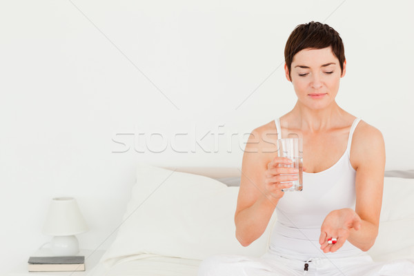 Stock photo: Charming woman taking pills in her bedroom