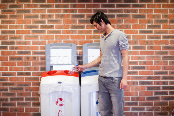 Stock photo: Young man recycling a plastic bottle