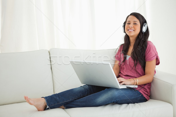 Smiling Latino student wears earphone using a laptop while sitting on a sofa Stock photo © wavebreak_media