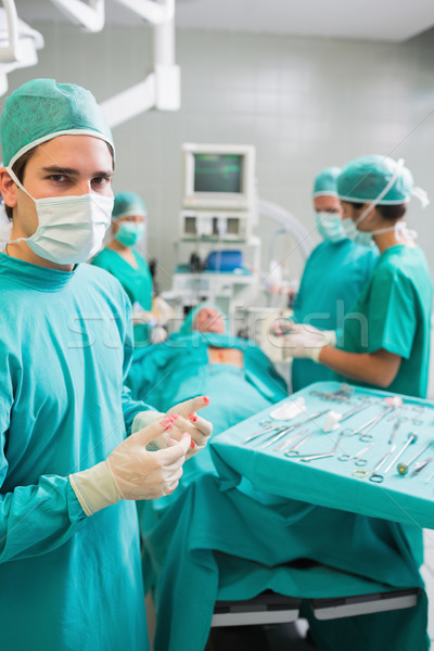 Surgeon wearing gloves with blood next to a patient in an operating theatre Stock photo © wavebreak_media