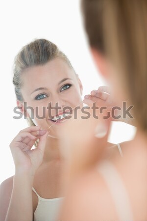 Woman using dental floss in front of mirror in the white background Stock photo © wavebreak_media