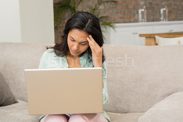 Unsmiling brunette using laptop Stock photo © wavebreak_media