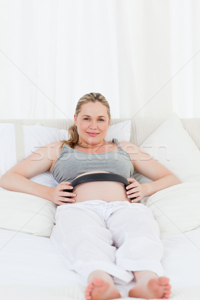 Pregnant woman putting her earphones on her belly at home Stock photo © wavebreak_media
