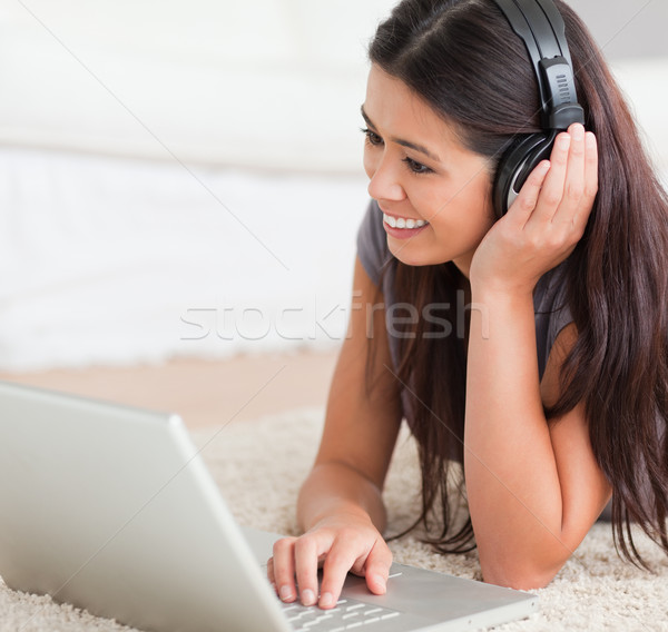 close up of a charming woman lying on a carpet with laptop and earphones in livingroom Stock photo © wavebreak_media