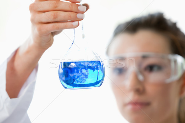 Close up of beautiful scientist looking at a flask with the camera focus on the object Stock photo © wavebreak_media