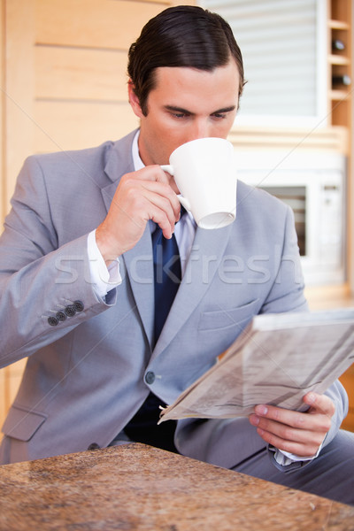 Stock photo: Young businessman reading news and having a coffee