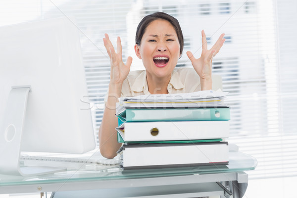 Stock photo: Angry businesswoman shouting with stack of folders at desk