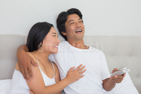 Souriant asian couple lit regarder tv [[stock_photo]] © wavebreak_media