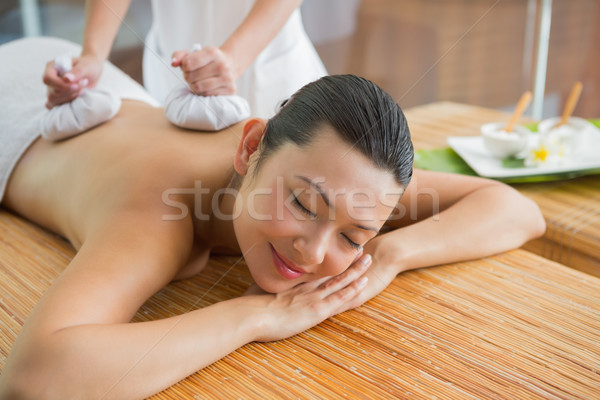Smiling brunette getting a herbal compress massage Stock photo © wavebreak_media