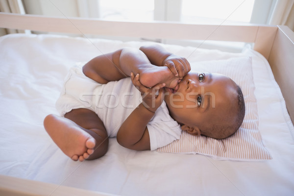 Adorable baby boy lying in his crib chewing foot Stock photo © wavebreak_media