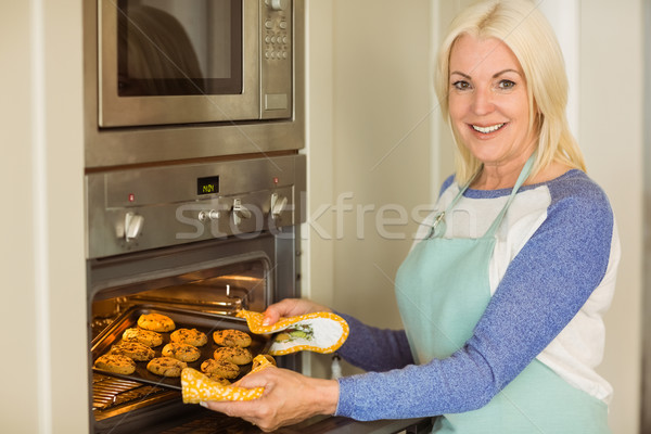Woman taking tray of fresh cookies out of oven Stock photo © wavebreak_media