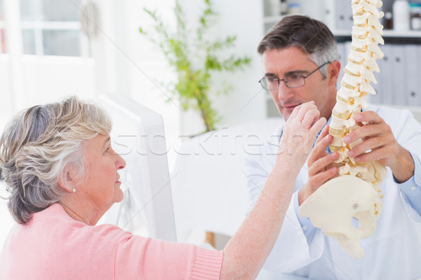 Stock photo: Patient looking at anatomical spine while doctor explaing her