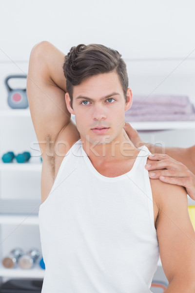 Doctor stretching a young man arm Stock photo © wavebreak_media
