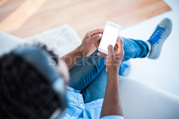 Stock photo: High angle view of man holding smartphone while sitting on sofa 