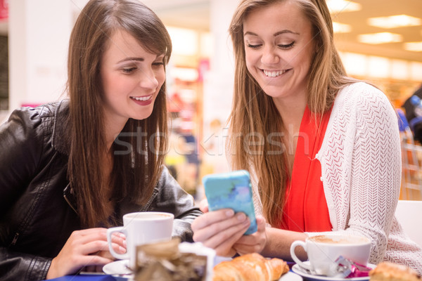 Due donne guardando cellulare snack caffè coffee shop Foto d'archivio © wavebreak_media