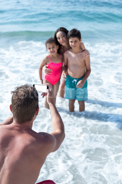 Man photographing children and wife in shallow water Stock photo © wavebreak_media