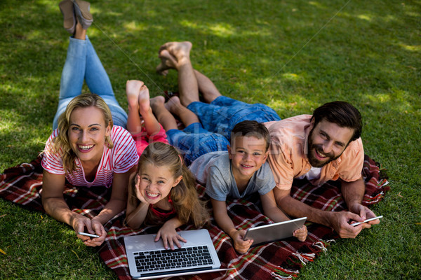 Smiling family using technologies while lying in yard  Stock photo © wavebreak_media