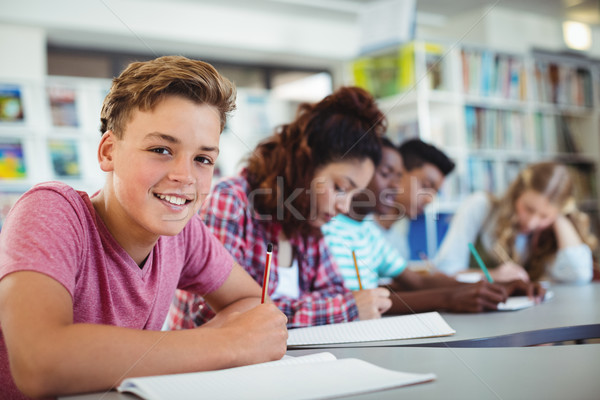Portrait of happy schoolboy studying in library Stock photo © wavebreak_media