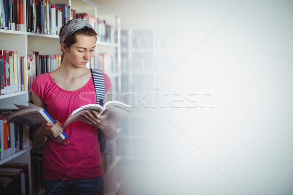 Stock photo: Attentive schoolgirl reading book in library