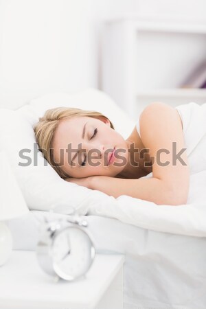 Gorgeous red-haired woman lying in bed not wanting to hear the alarm clock in her bedroom Stock photo © wavebreak_media