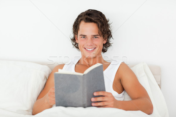 Handsome man holding a book in his bedroom Stock photo © wavebreak_media