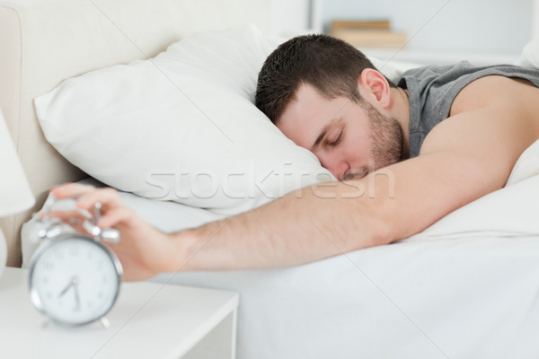 Sleeping man being awakened by an alarm clock in his bedroom Stock photo © wavebreak_media