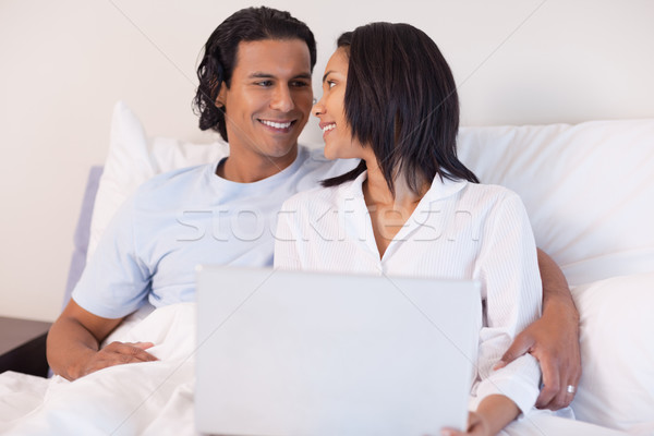 Smiling young couple sitting on the bed with their laptop Stock photo © wavebreak_media