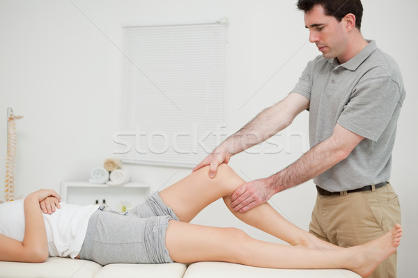 Physiotherapist examining the knee of his patient while touching it in a room Stock photo © wavebreak_media