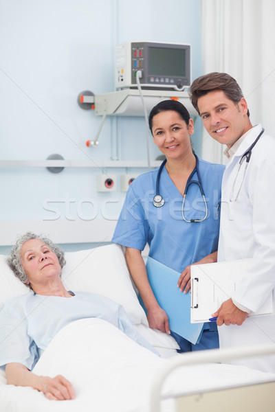 Patient with her doctor and nurse looking at camera in hospital ward Stock photo © wavebreak_media