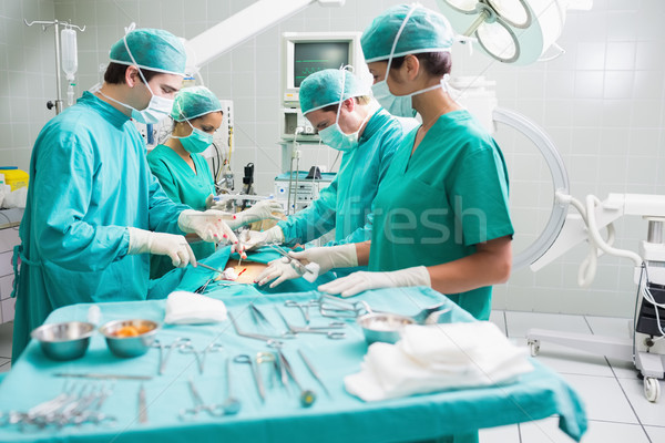 Stock photo: Side view of a surgical team operating a patient in an operation theatre