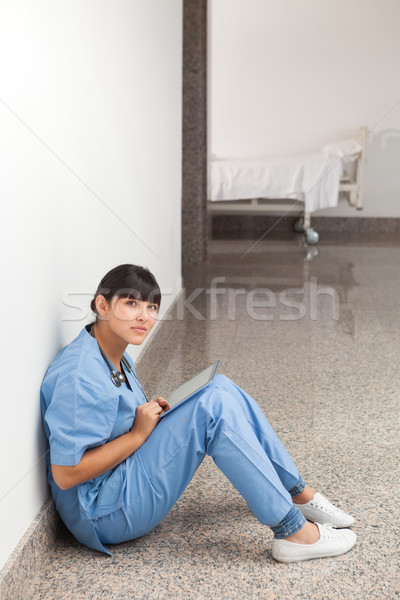 Nurse sitting on the ground in the hospital hallway with tablet computer Stock photo © wavebreak_media
