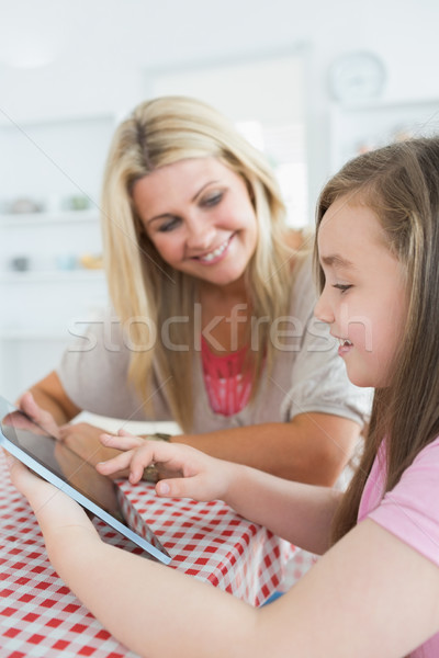 Stock photo: Mother and little girl using a tablet pc while smiling in the kitchen