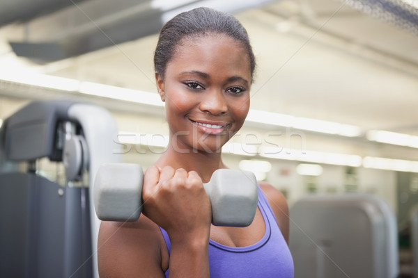 Fit woman smiling at camera holding dumbbell Stock photo © wavebreak_media