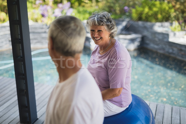 Smiling senior woman looking at man while sitting on exercise ball Stock photo © wavebreak_media