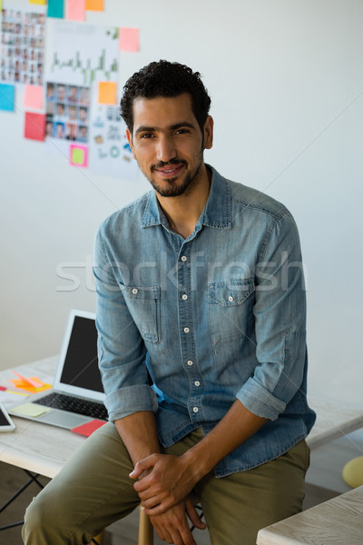 Portrait of man sitting on desk at office Stock photo © wavebreak_media
