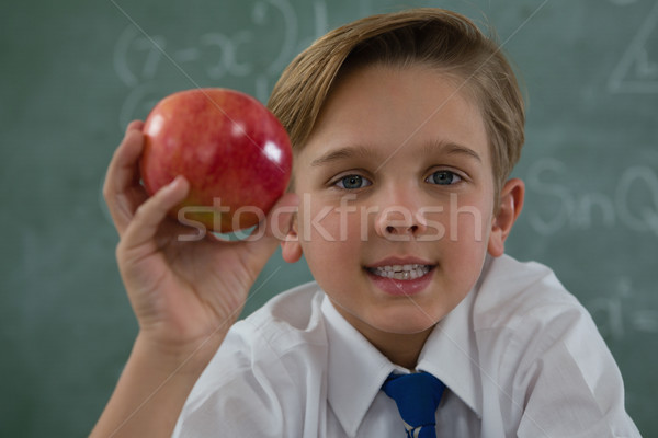 Schoolboy holding red apple against chalkboard Stock photo © wavebreak_media
