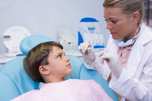 Stock photo: Dentist holding medical equipment while talking to boy