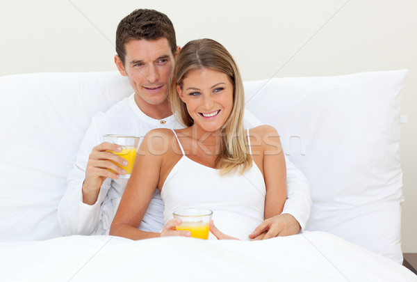 Affectionate couple drinking orange juice lying on their bed Stock photo © wavebreak_media