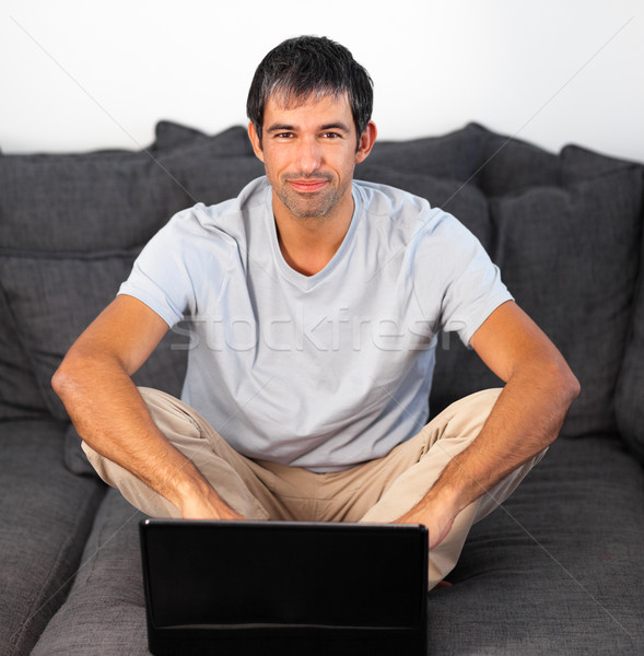 Delighted man using a laptop on a grey sofa Stock photo © wavebreak_media