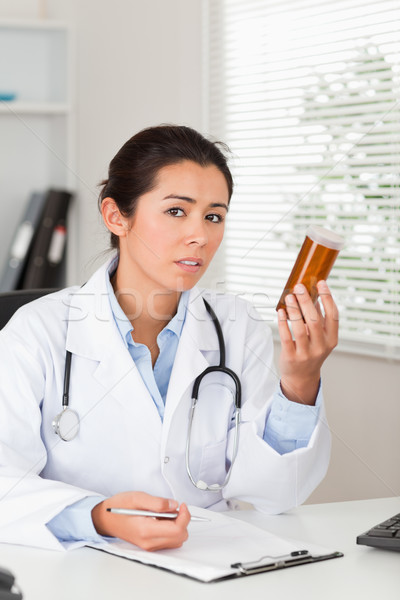 Pretty worried doctor holding a box of pills in her office Stock photo © wavebreak_media