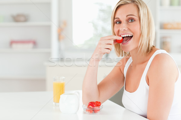 Young woman sitting at table eats strawberries in the kitchen Stock photo © wavebreak_media