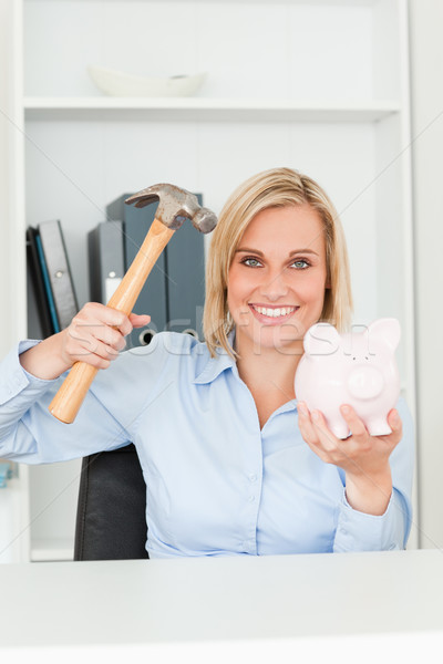 Happy woman wanting to destroy her piggy bank in her office Stock photo © wavebreak_media