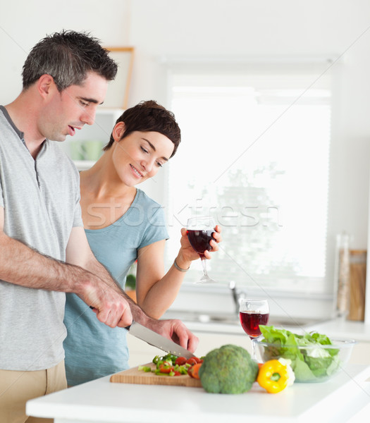 Handsome Man cutting vegetables while is woman is watching in a kitchen Stock photo © wavebreak_media