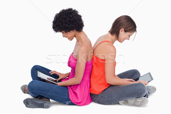 Side view of teenagers sitting cross-legged back to back with a tablet computer Stock photo © wavebreak_media