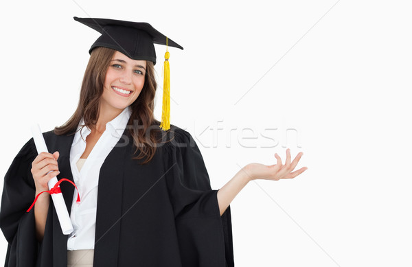 A smiling woman with a degree in hand as she has graduated and looks at the camera with a hand out a Stock photo © wavebreak_media