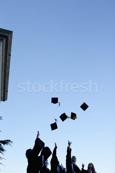 Low Angle Shot Of Five Grad Students Throwing Their Hats In The