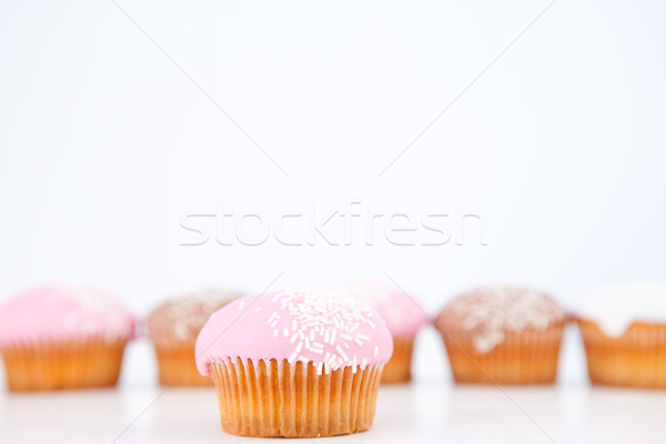 Stock photo: Many muffins with icing sugar lined up against a white background